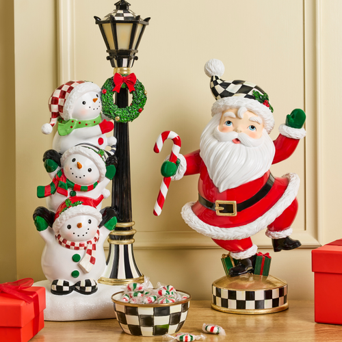 Holiday Twinkly Toes Santa figurine with a candy cane next to a snowman lamp post and candy bowl.