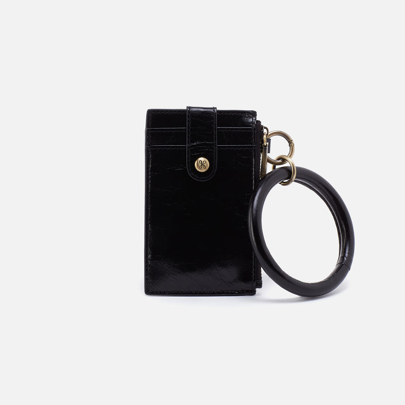 Black leather ring credit card wristlet with antique brass hardware and a circular handle.