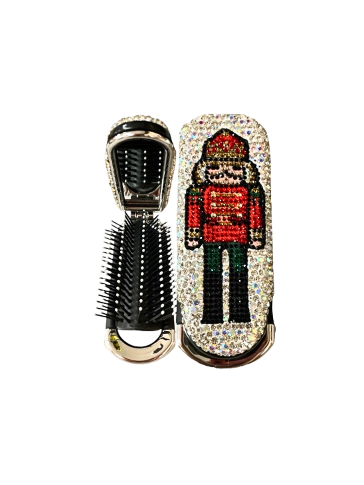 Folding hair brush and mirror set with a rhinestone nutcracker design on a silver frame.
