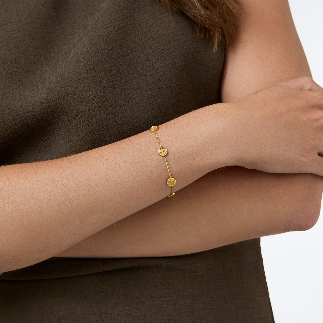 Delicate gold chain bracelet with five small coin stations on adjustable length.