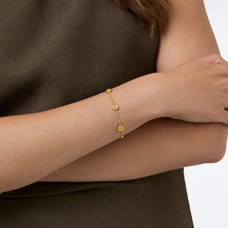 Delicate gold chain bracelet with five small coin stations on adjustable length.