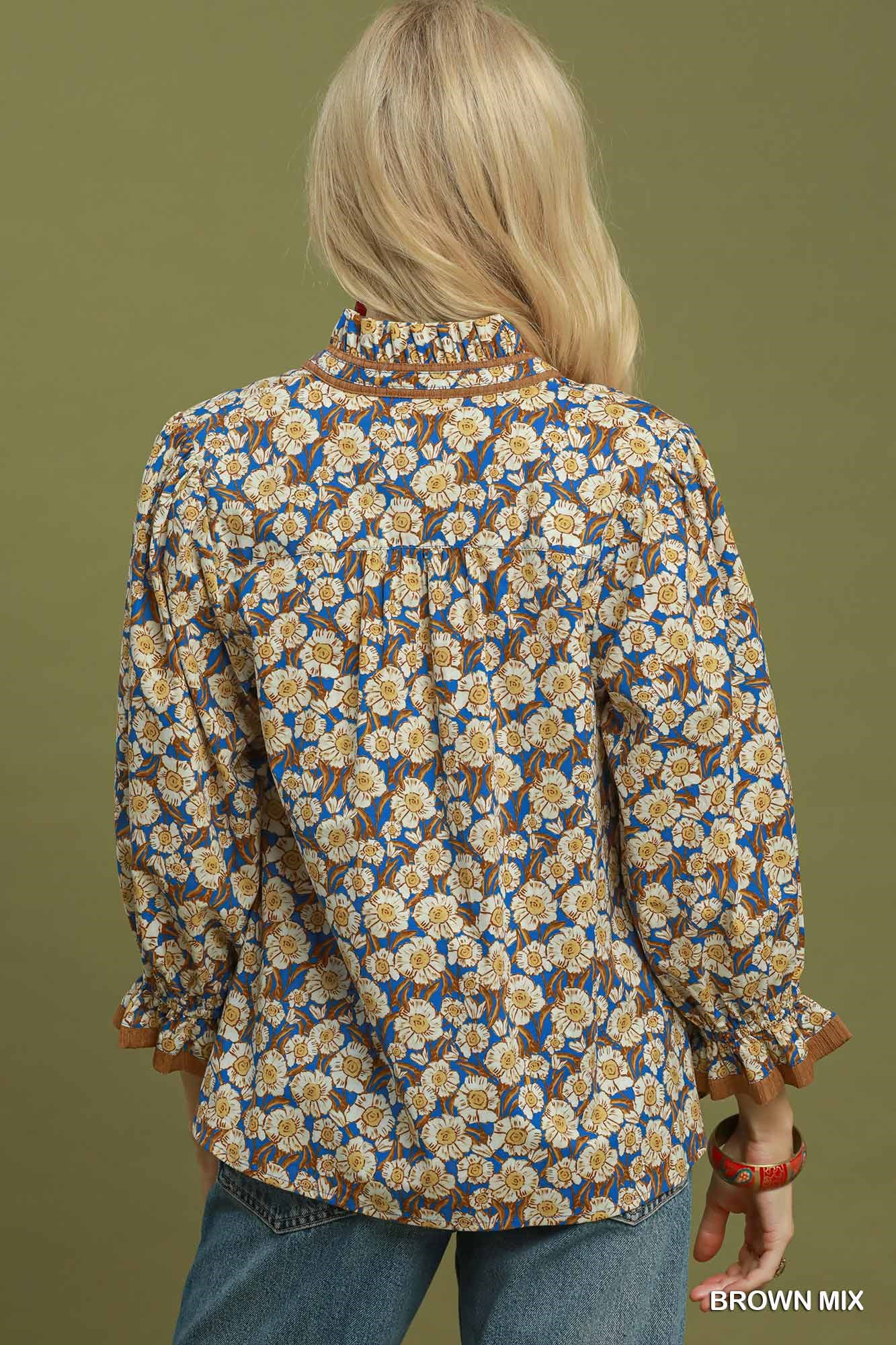 Back view of a woman wearing a blue and brown floral print blouse with a ruffled mandarin collar.