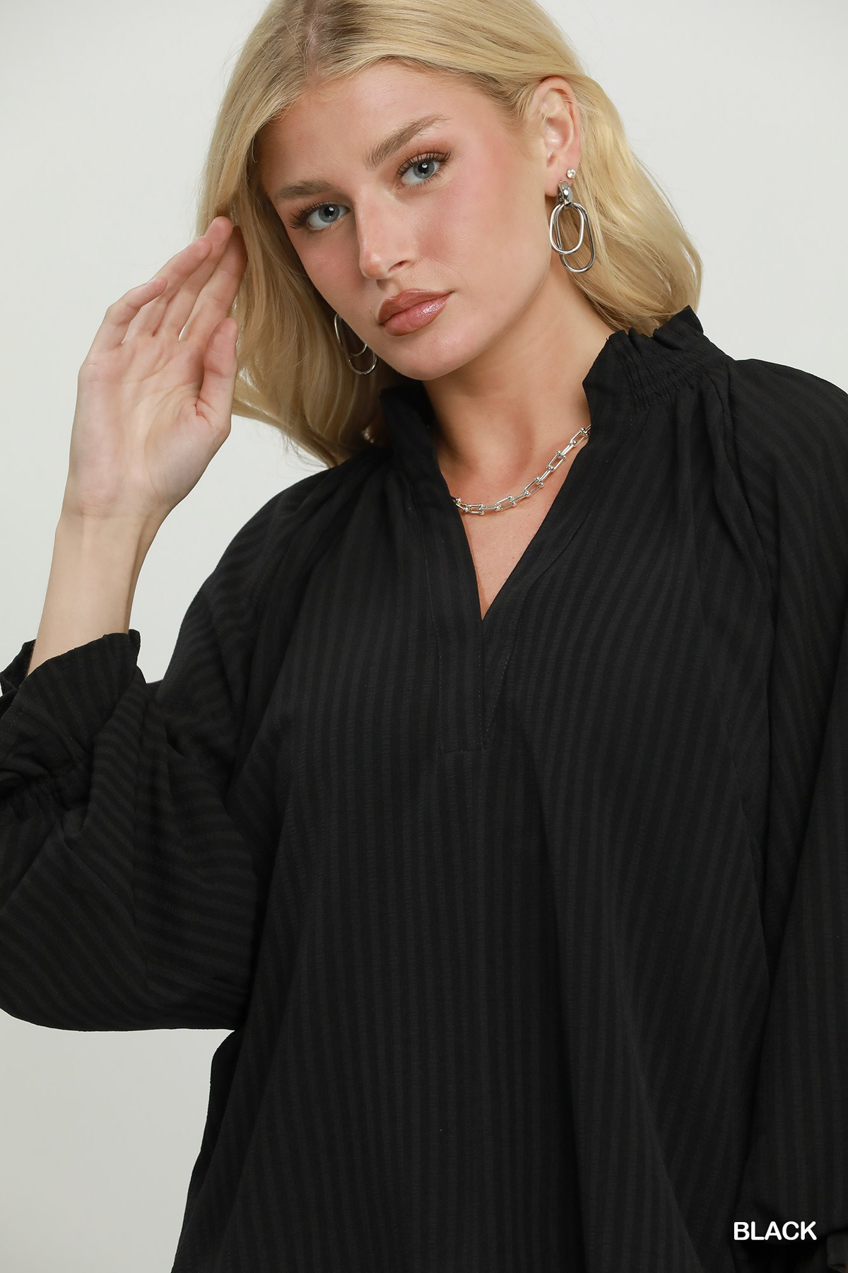 Close-up of a woman wearing the Emma Stripe Split Neck Blouse in black with a ruffled collar.