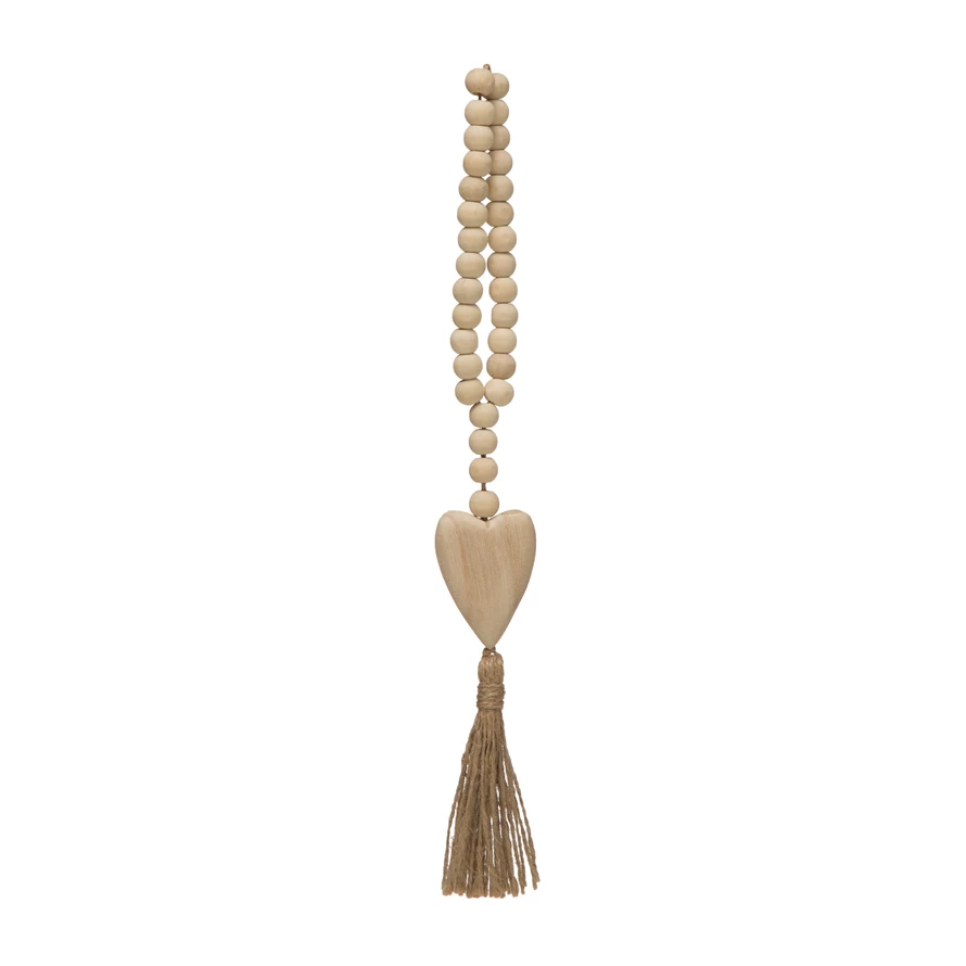 Wood bead necklace with heart icon pendant and jute tassel on a light background