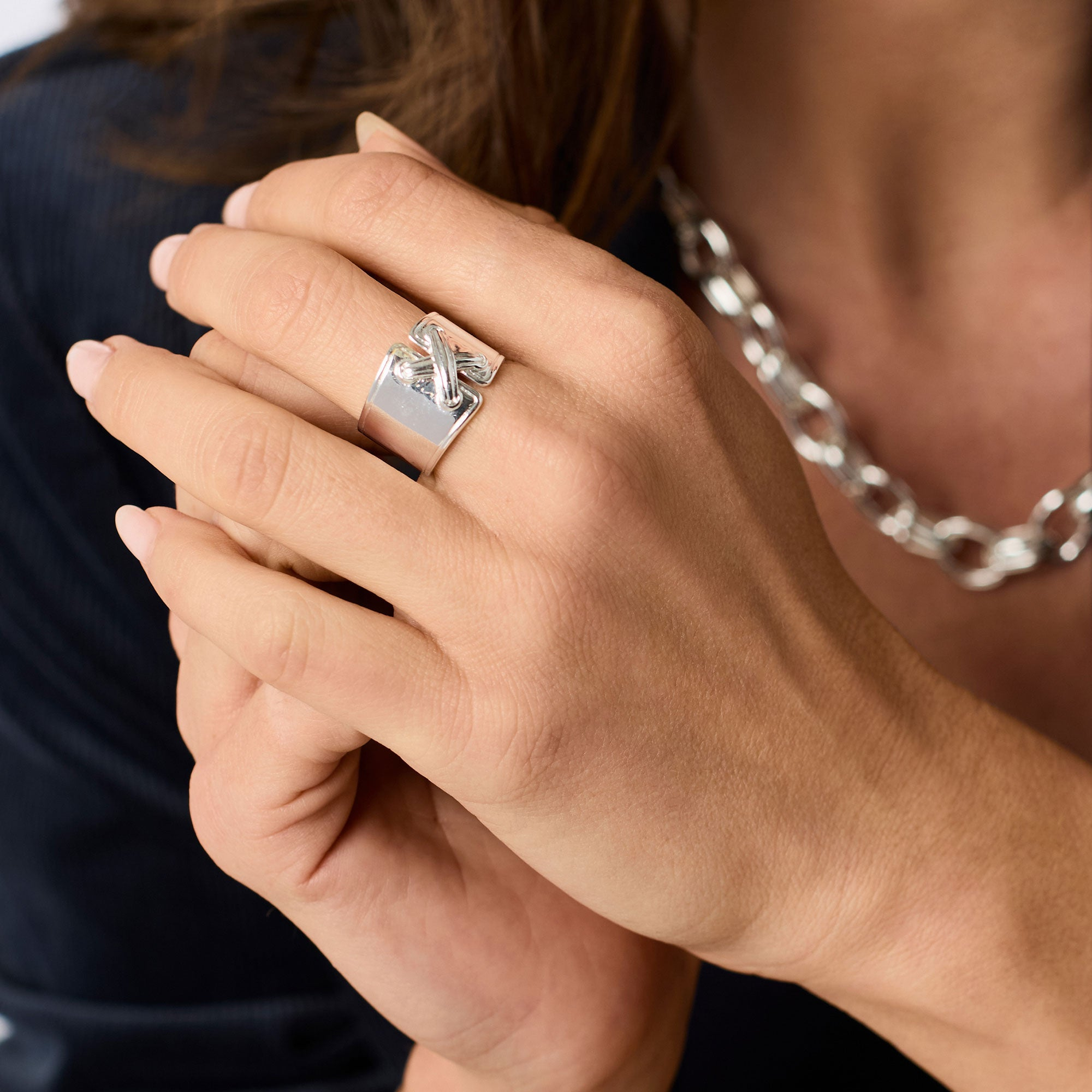 A person wearing the adjustable Essex Ring in silver, featuring a wide band and knotted detail.