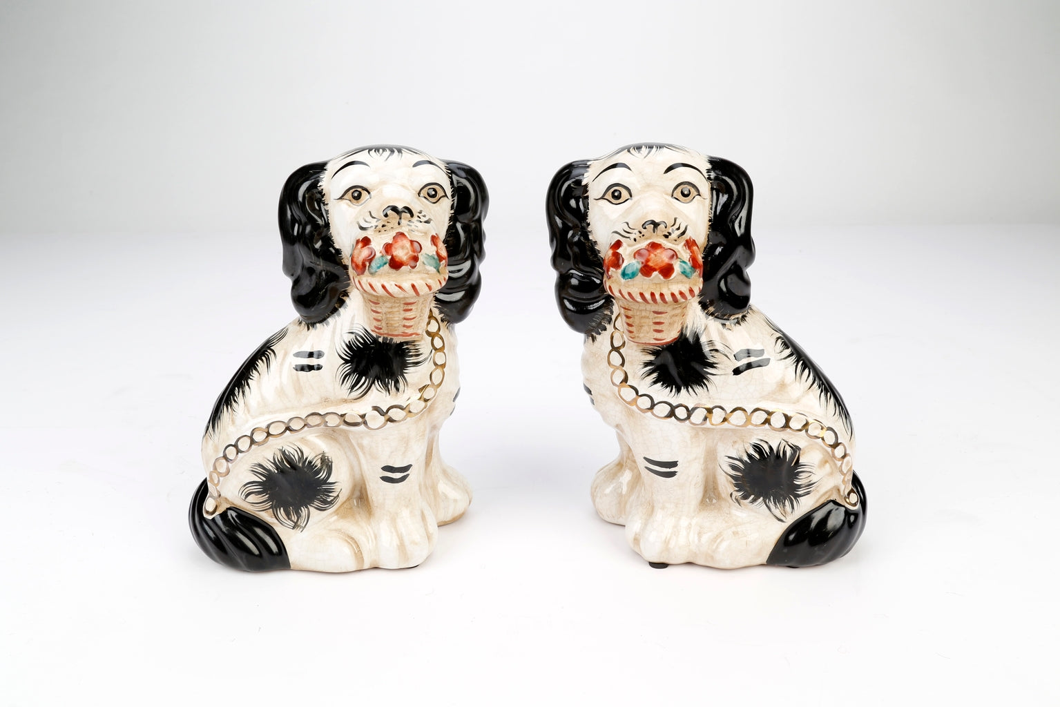Set of two Staffordshire dog figurines in black with white floral baskets