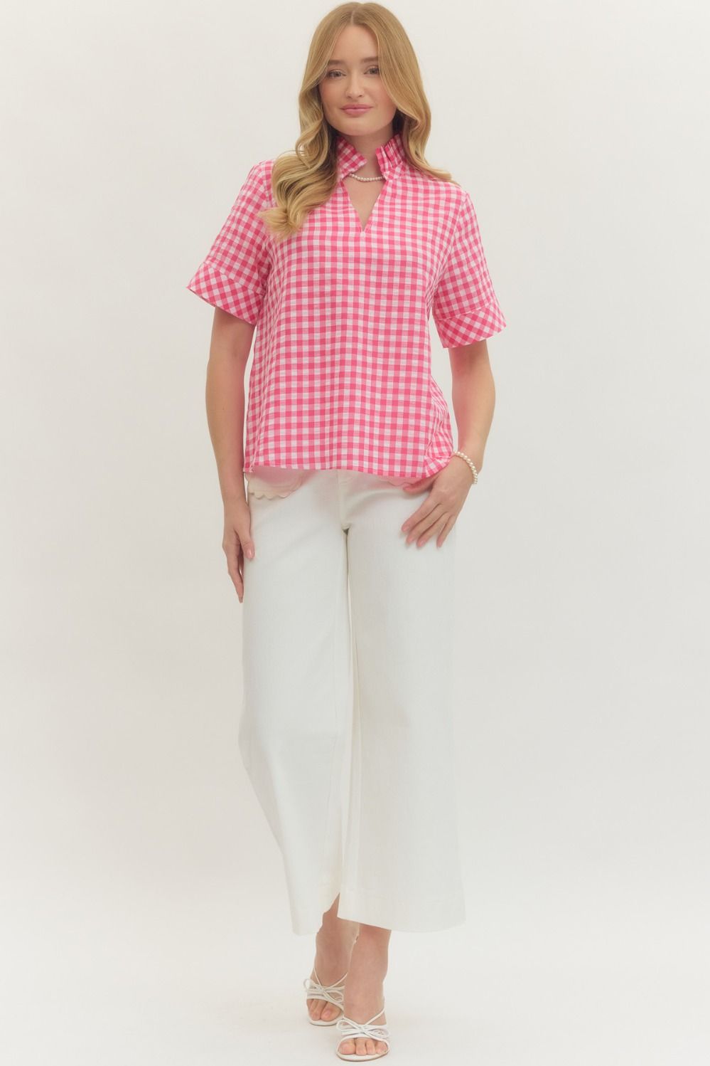 Woman wearing a pink and white Natalie Gingham Short Sleeve Top with a stand collar and V-neck.