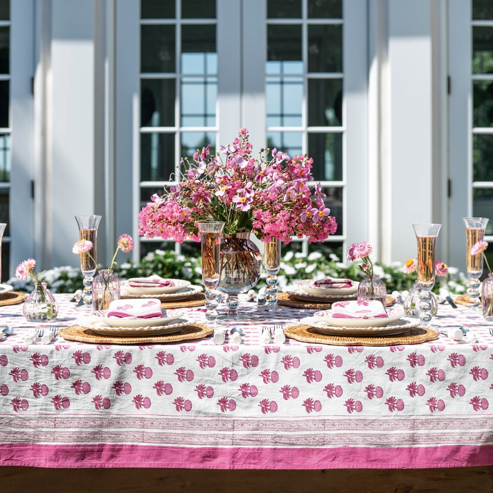 Rosé Tablecloth with pink floral patterns on a set outdoor dining table with floral centerpieces.