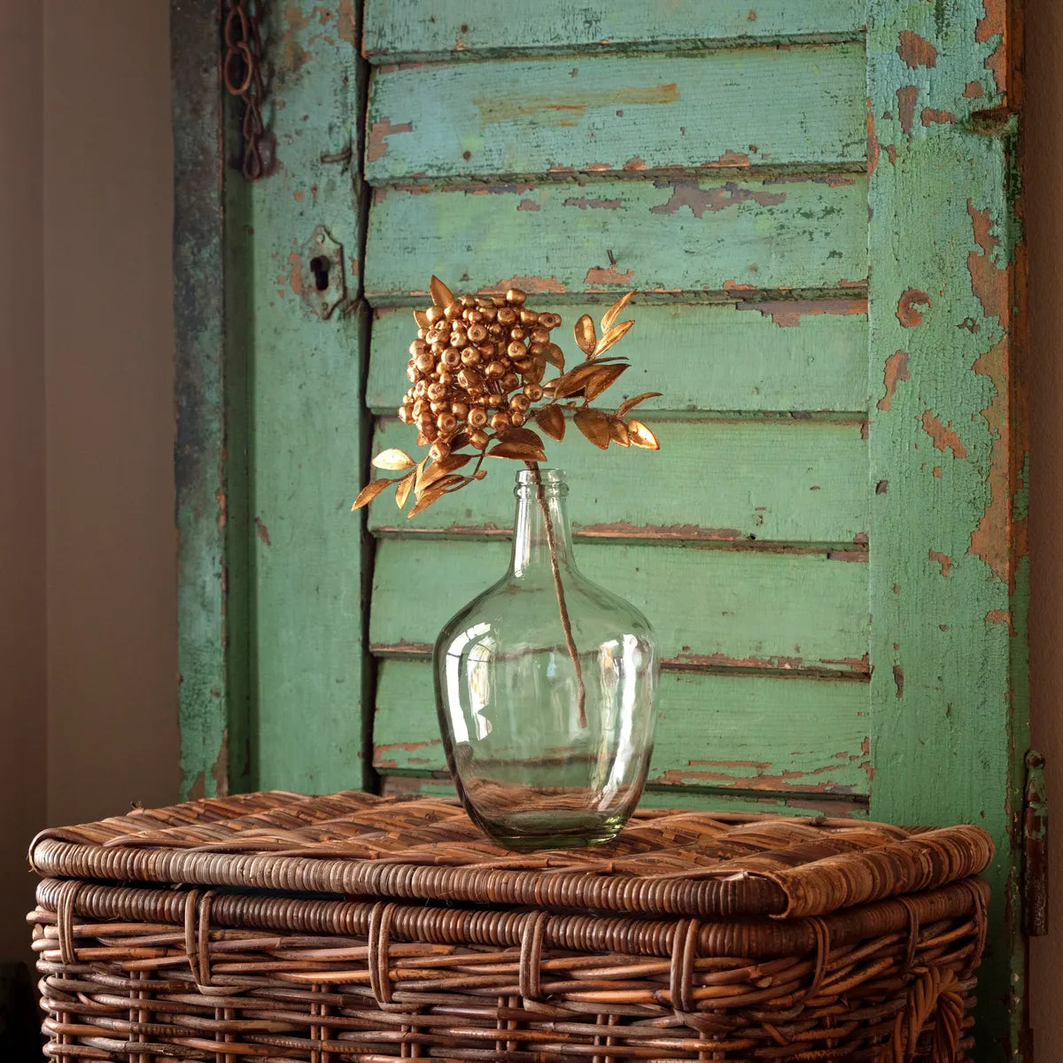 Antique Gold Metallic Berry Bunch in a clear glass vase on a wicker basket.