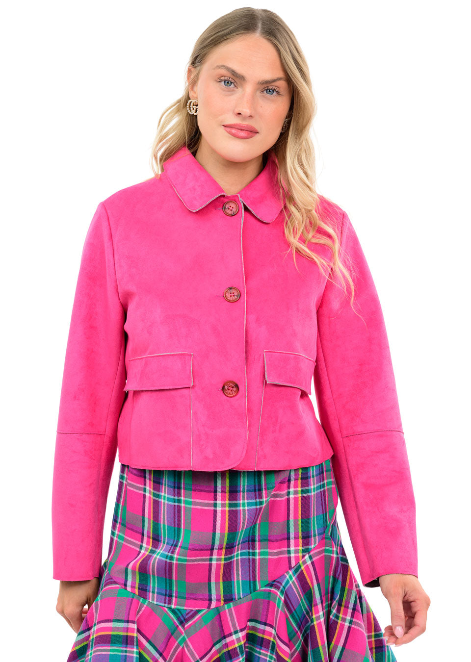 Woman wearing a bright pink Althea suede jacket with patch pockets and a plaid skirt.
