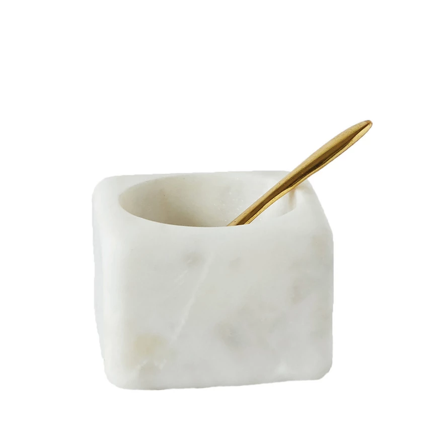 Square white marble bowl with a small gold brass spoon resting inside.
