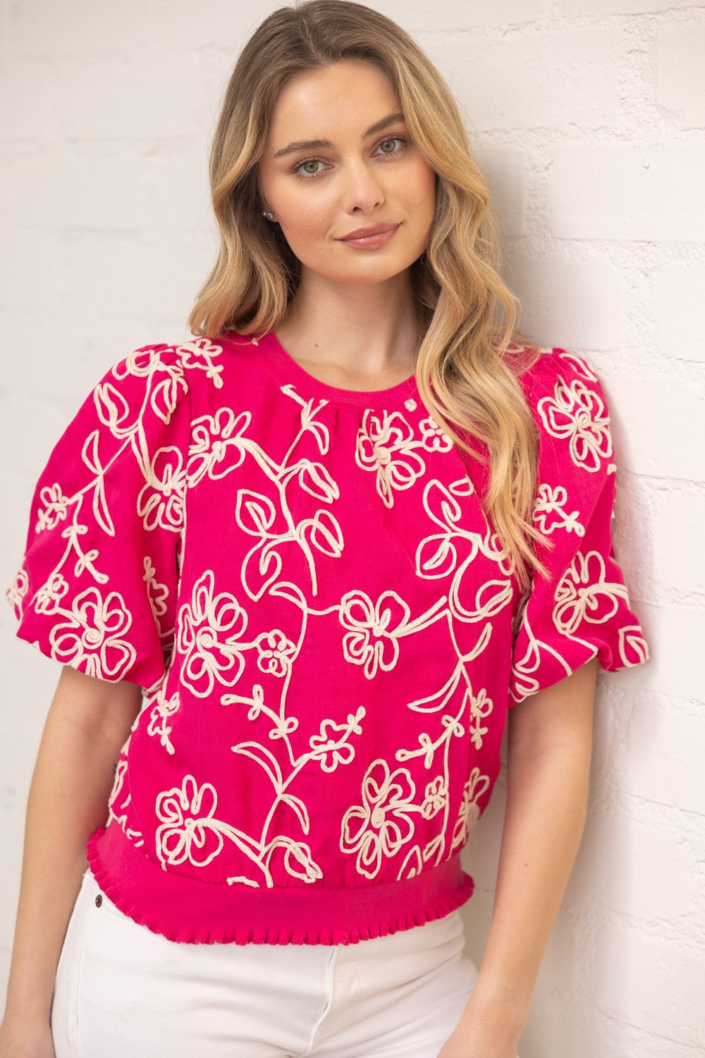 Natty floral embroidered woven top with short bubble sleeves, round neckline, ruffled hem, and relaxed fit in a soft neutral tone.
