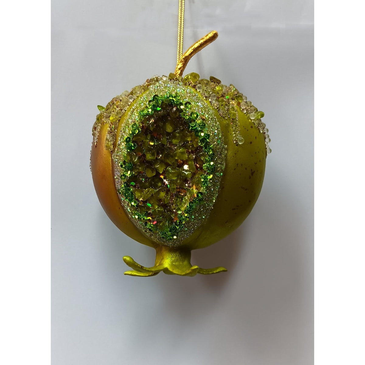 Green pomegranate ornament with a split-open center filled with shimmering faux seeds and a hanger.