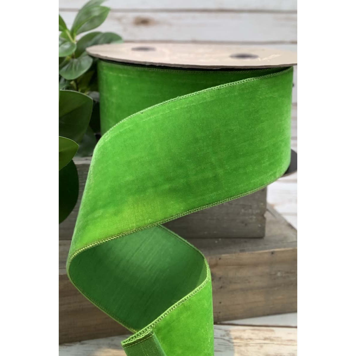 Bright green velvet ribbon with a faux dupion back on a spool.