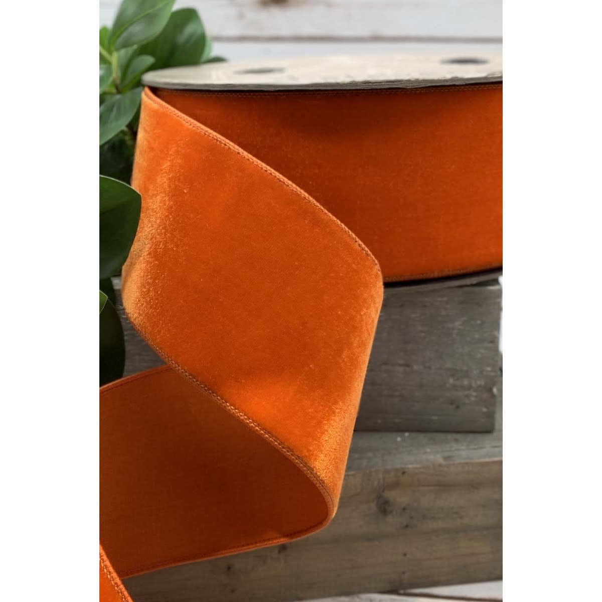 Bright orange velvet ribbon on a spool with a faux dupion back.