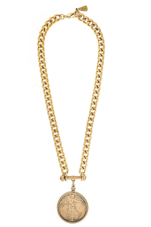 Cora Coin Necklace featuring a gold-toned curb chain and a round angel-embossed coin pendant.