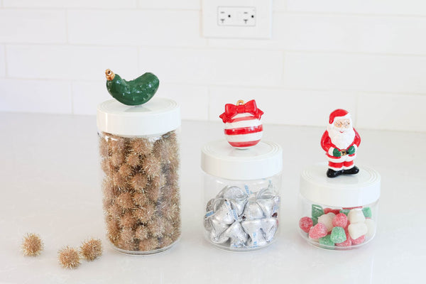 Three Pinstripes Canisters in varying sizes with Christmas-themed lids holding holiday treats.