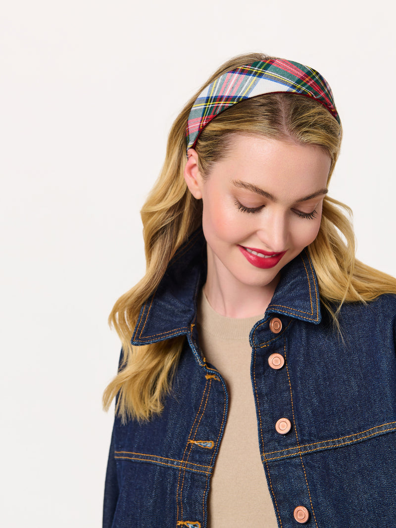 A woman wearing a plaid wide headband in a red, green, and white tartan pattern with a denim jacket.