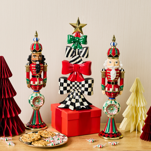 A decorative holiday tree made of stacked green, striped, red, and checkered bows on a red gift box.