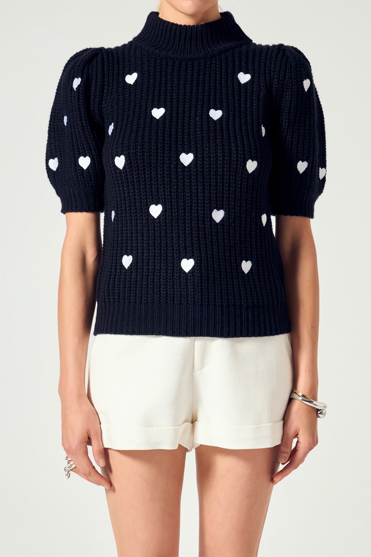 Sierra Heart Shape Embroidery Sweater in black with white hearts, mock neck, and puffy sleeves.