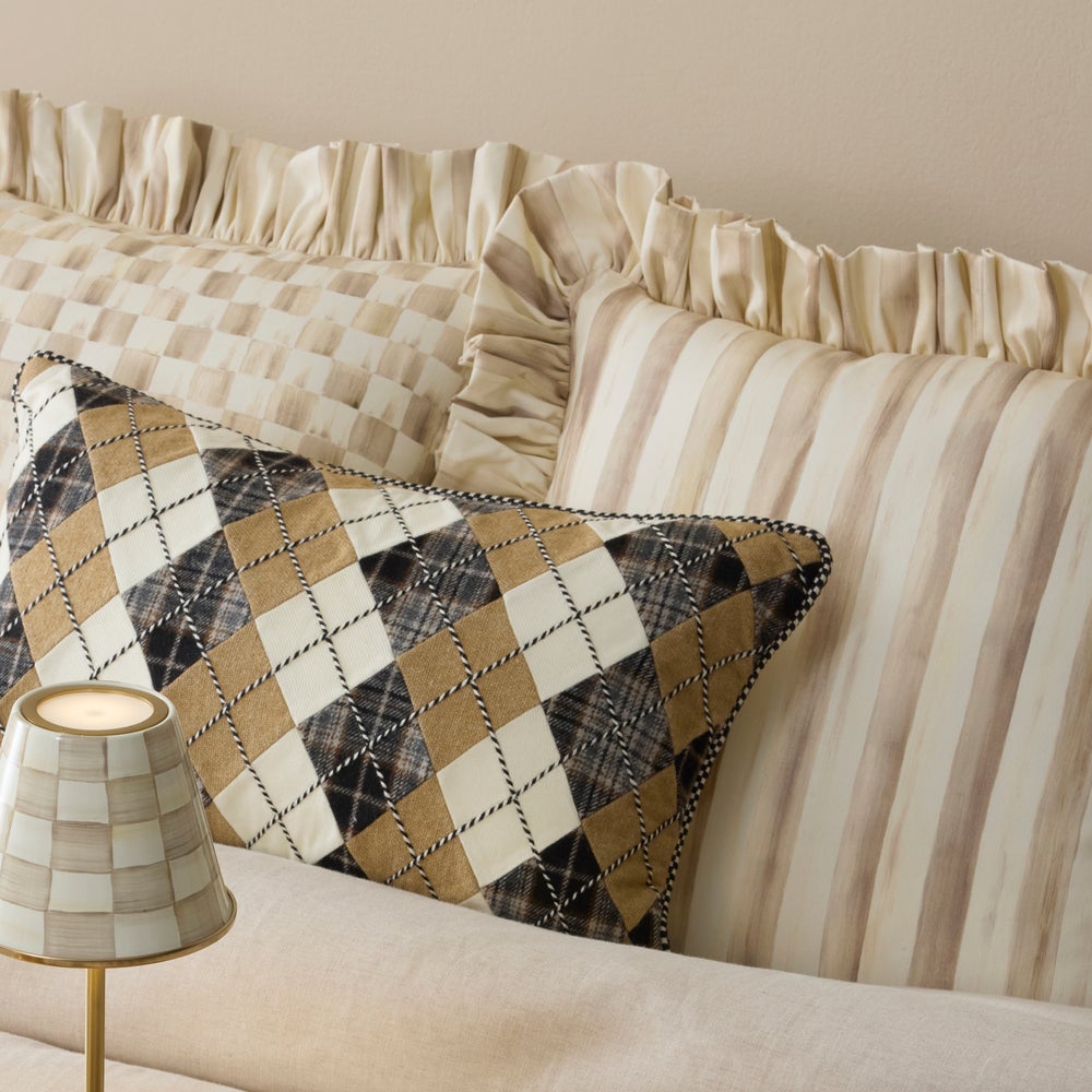Mocha Stripe Throw Pillow with Ruffle alongside an argyle pattern pillow and a small lamp.