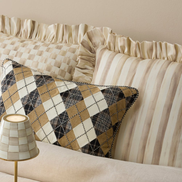 Mocha Stripe Throw Pillow with Ruffle alongside an argyle pattern pillow and a small lamp.