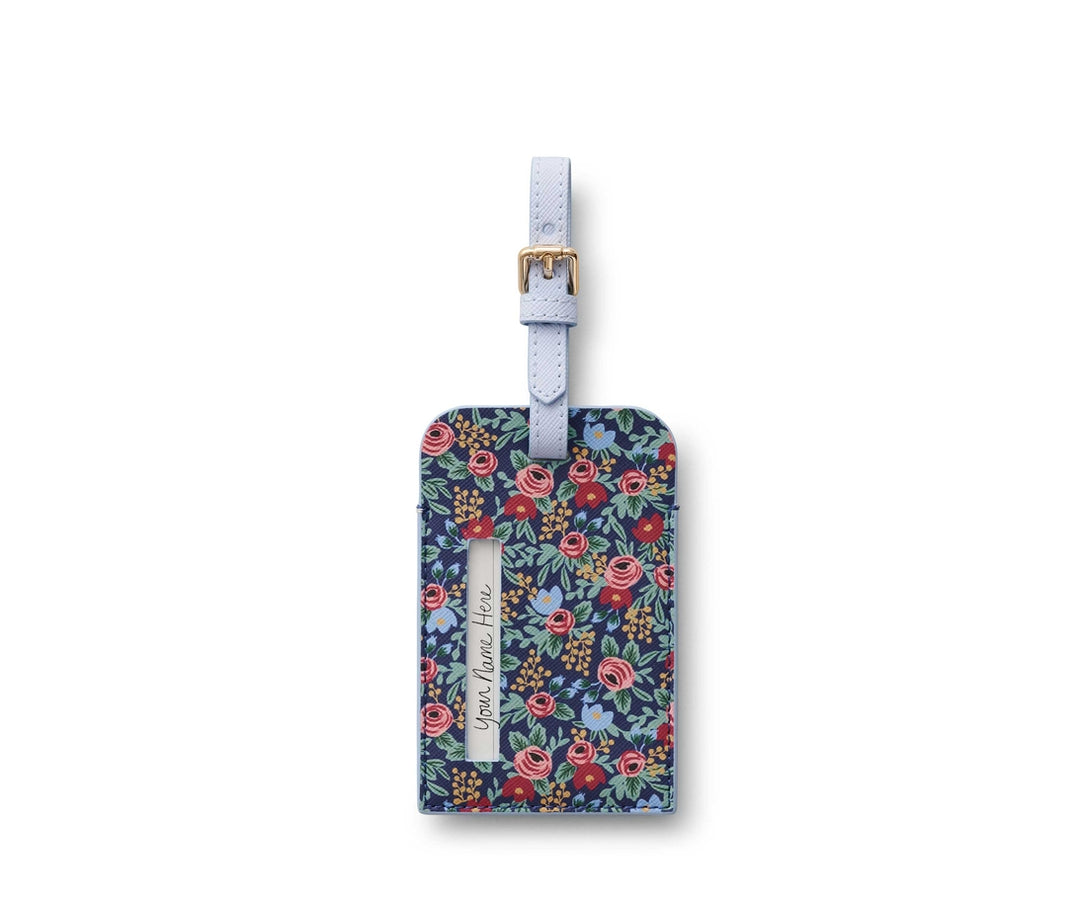 Rosa Luggage Tag with a dark blue floral pattern, light blue strap, and gold buckle.
