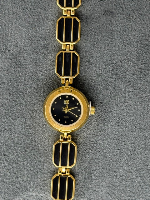 Ladies watch with a round gold-tone dial and a black enamel link bracelet on a gray background.