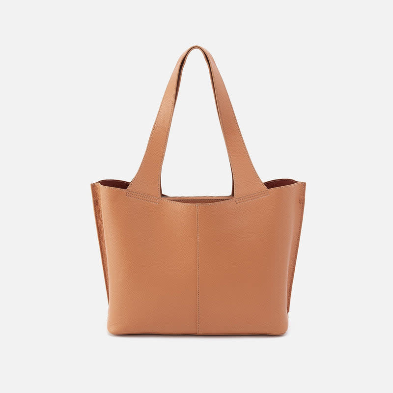 Biscuit-colored Vida tote bag with coconut shell interior lining, brass hardware, and double leather straps.