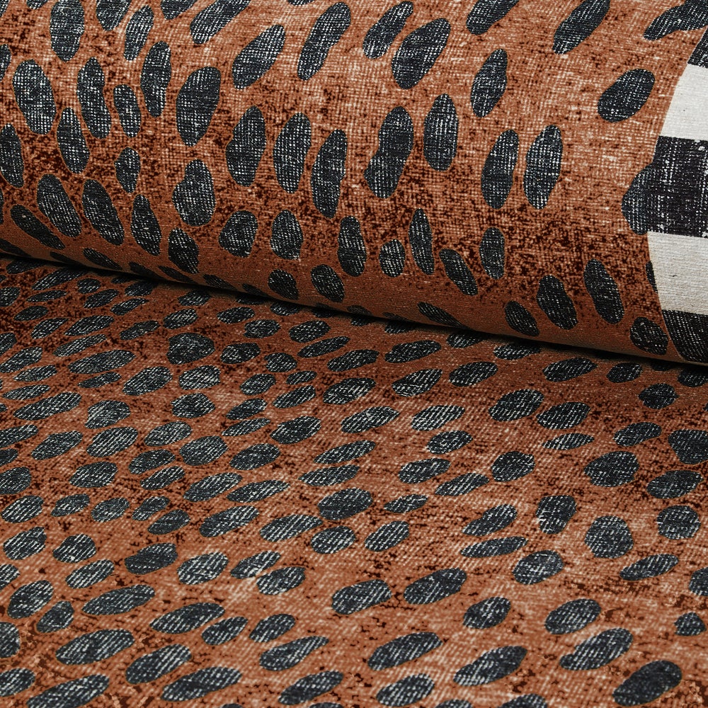 Close-up of a Cheetah 2' x 3' washable rug featuring a brown base with black oval spots.
