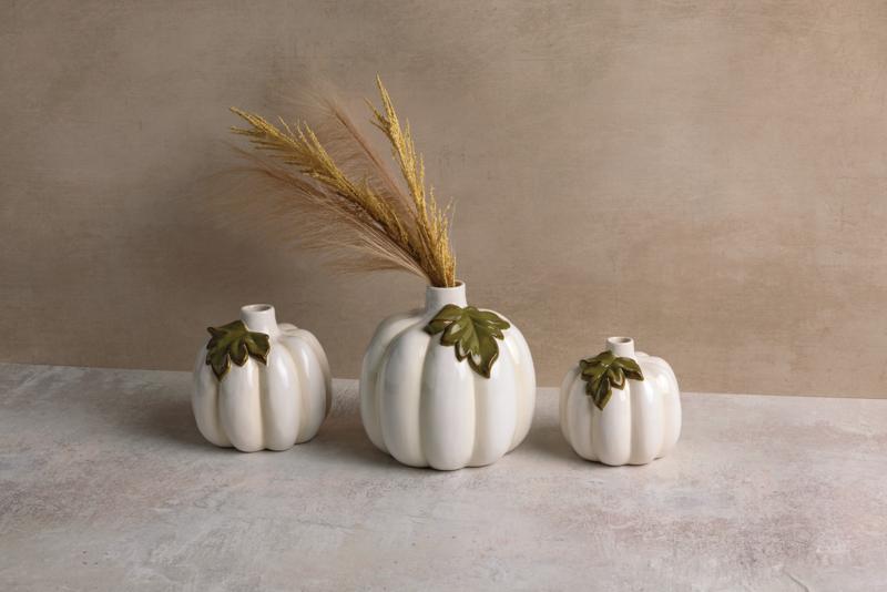 Three white ceramic pumpkin bud vases in varying sizes with green leaf accents and dried grass.