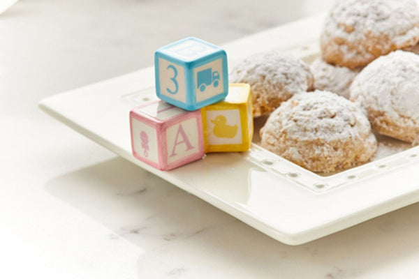 White ceramic platter with powdered sugar cookies and decorative baby blocks.