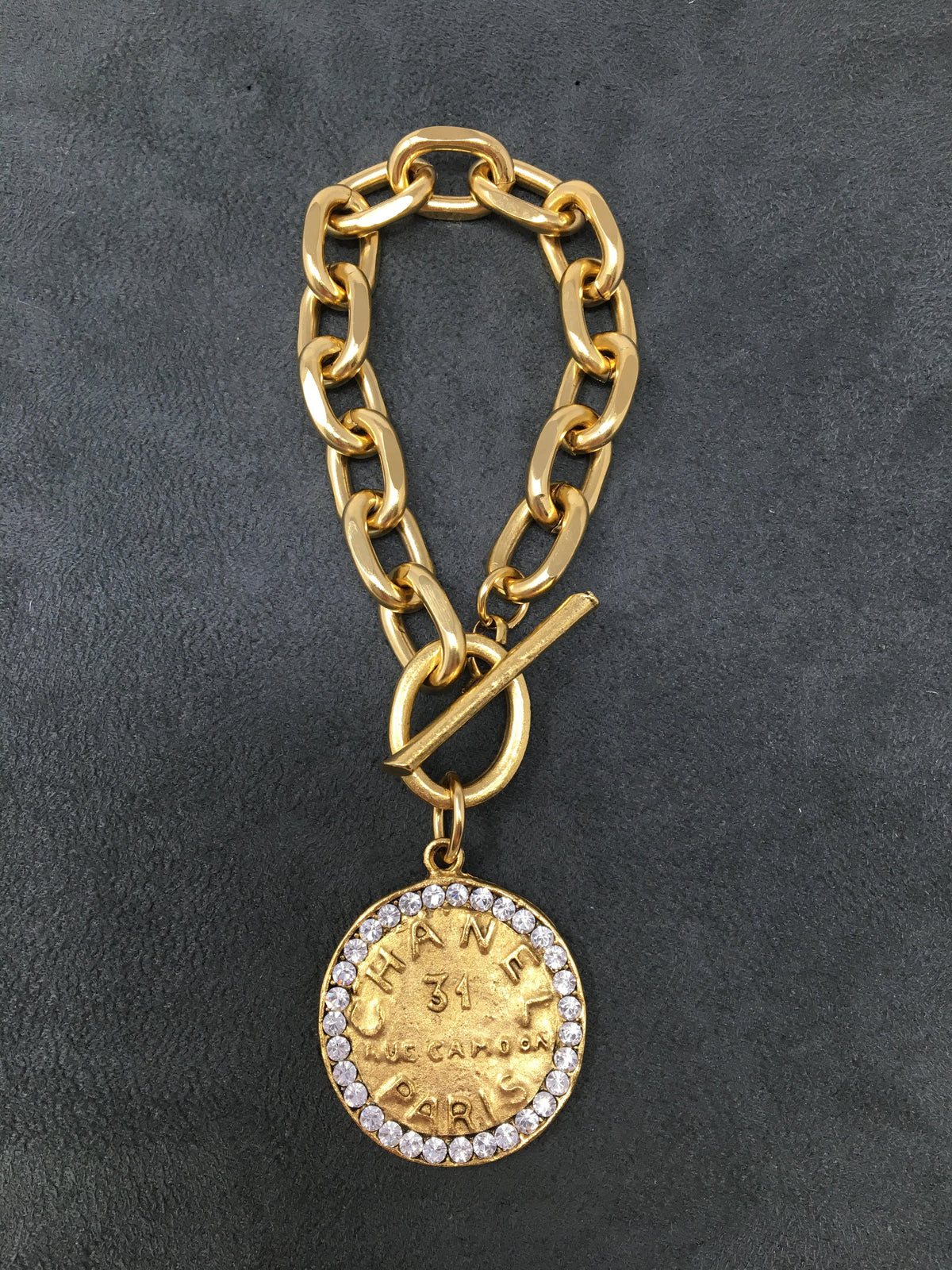 4-inch gold link bracelet with toggle clasp featuring a rhinestone-encrusted coin pendant.