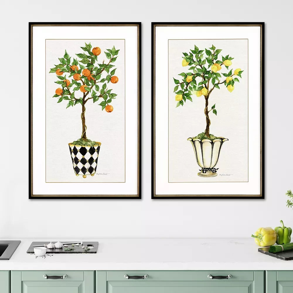 Two framed watercolor prints of orange and lemon topiary trees in decorative pots on a white wall.
