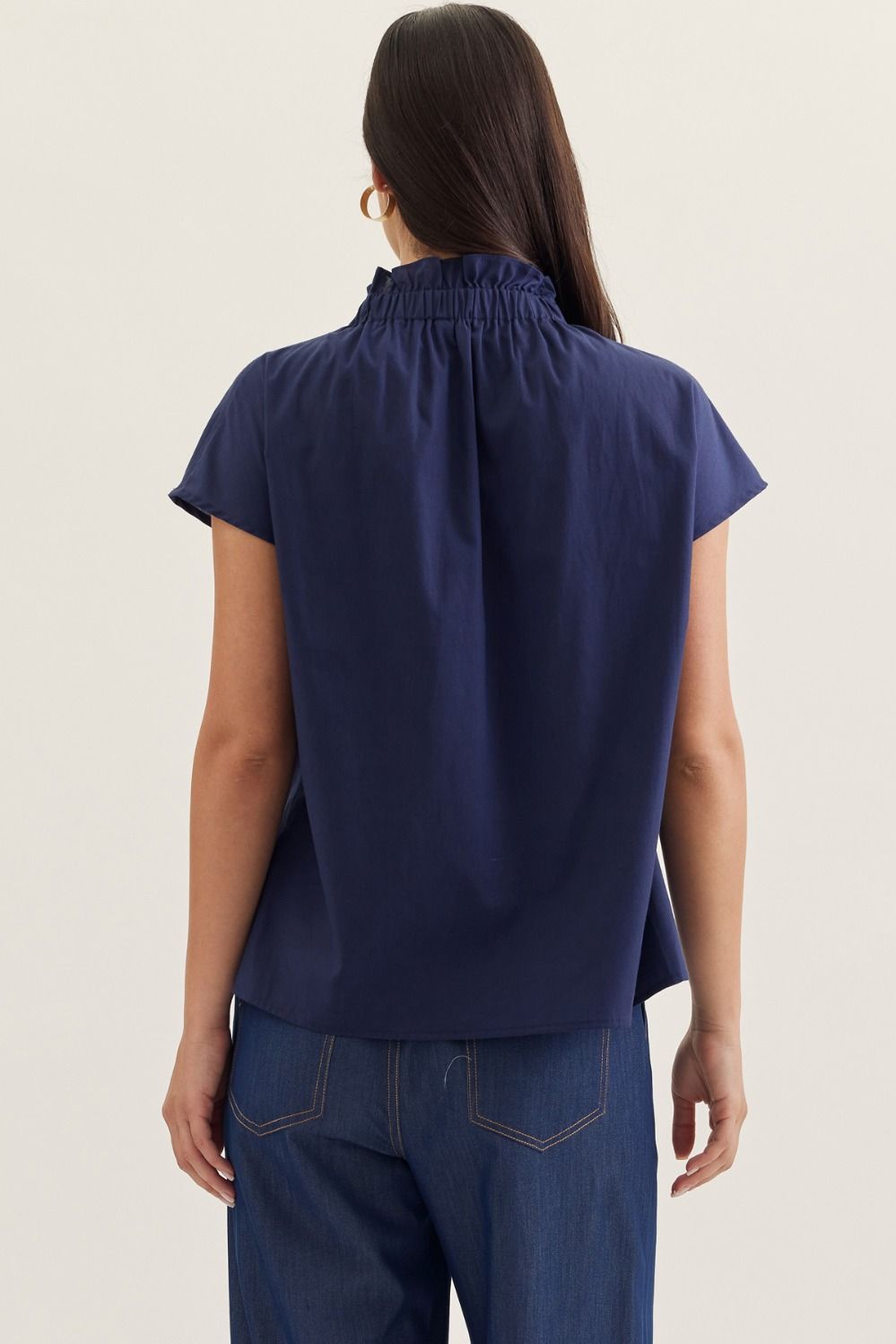 Aliana solid cap sleeve top in light beige with ruffled stand collar and button front closure.
