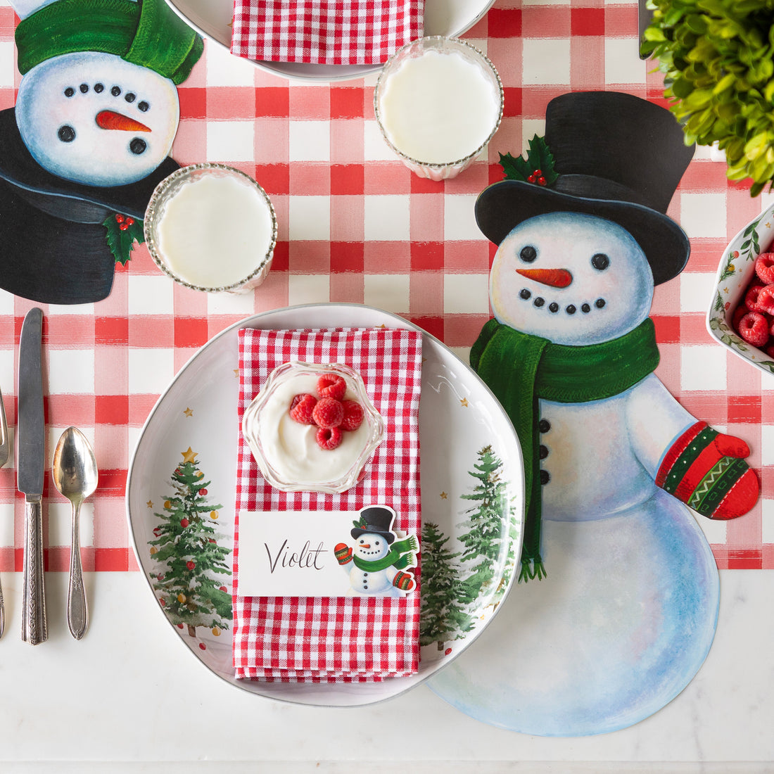 Die-cut snowman paper placemat with a festive winter scene pattern on recycled material.