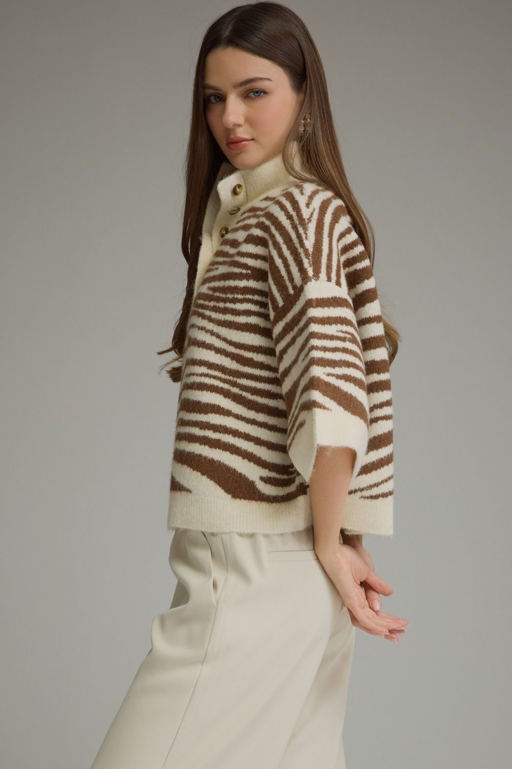 Woman wearing a Chanice abstract animal print 3/4 sleeve knit top with a stand neck and buttons.