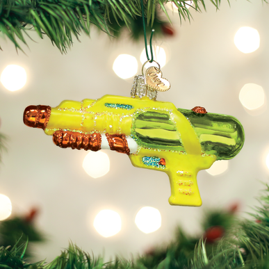 Yellow and green glass squirt gun Christmas ornament with glitter accents hanging on a tree.