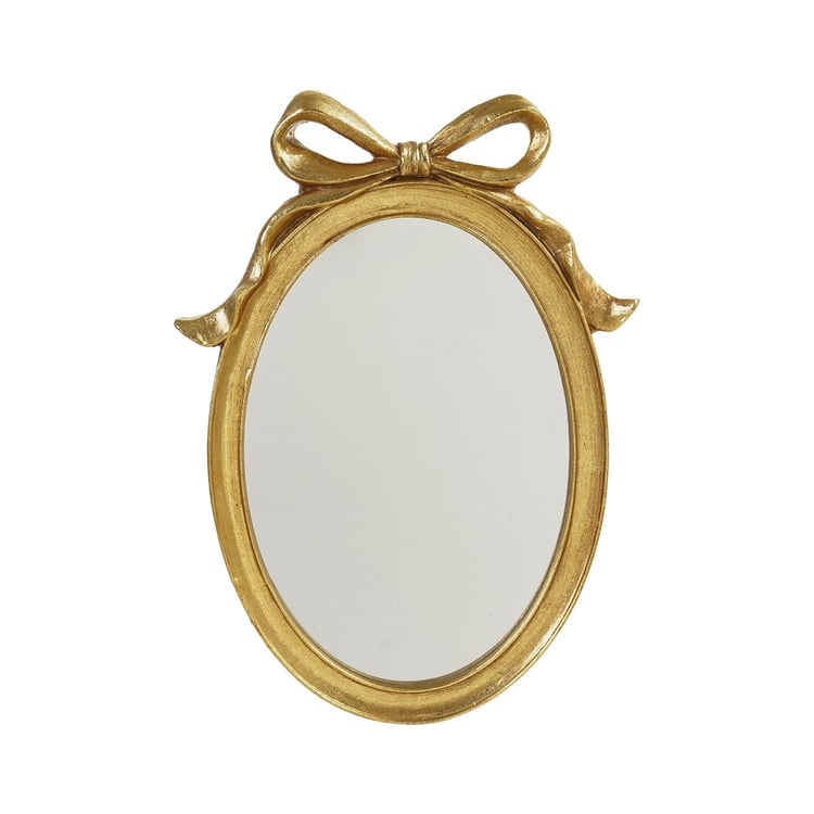 Oval gold resin framed wall mirror with a decorative bow detail at the top.