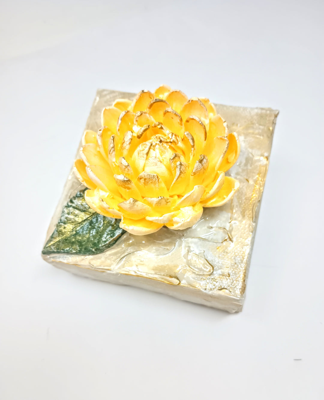 Square clay mum artwork featuring a sculpted floral relief in earthy tones on a textured surface.