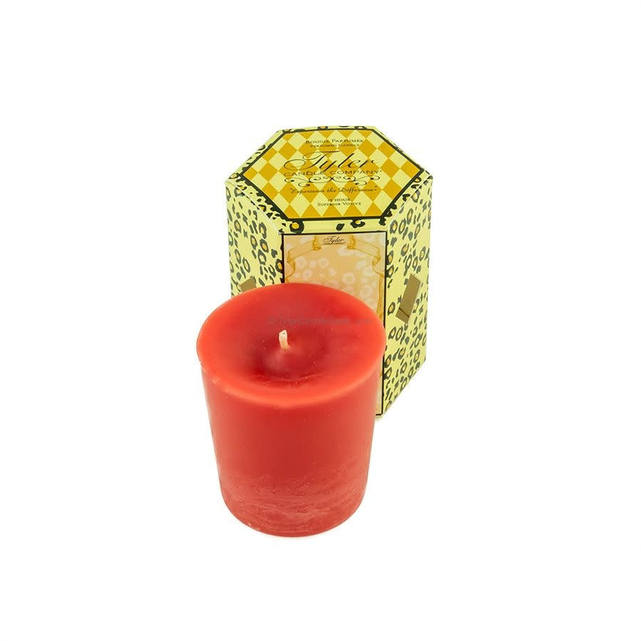 Red votive candle in front of a yellow leopard print box by Tyler Candle Company.