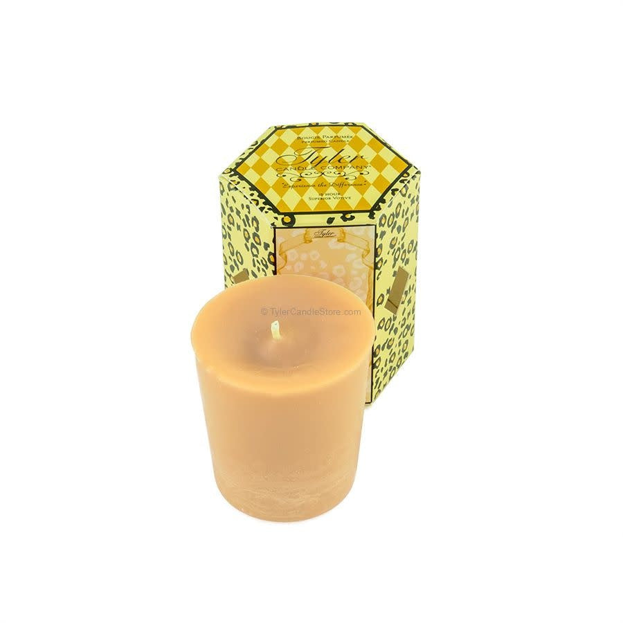 A 2oz Tyler votive candle in a light tan color, standing in front of its leopard-print box.