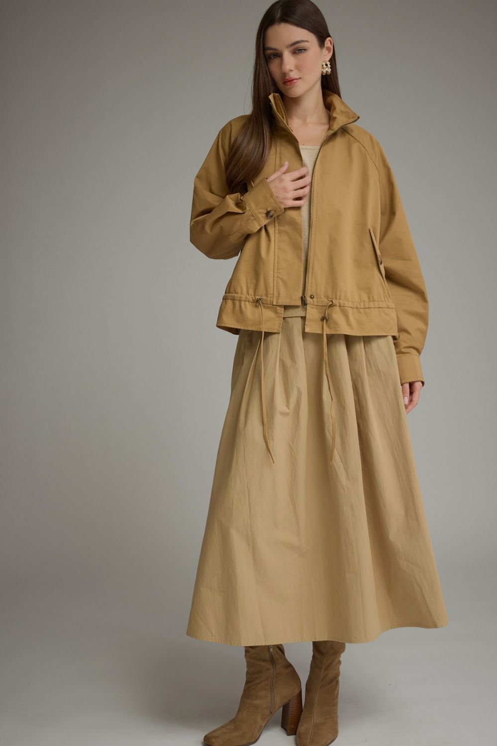 Woman wearing the Andrea Solid Long Sleeve Jacket in tan with a stand neck and drawstring hem.