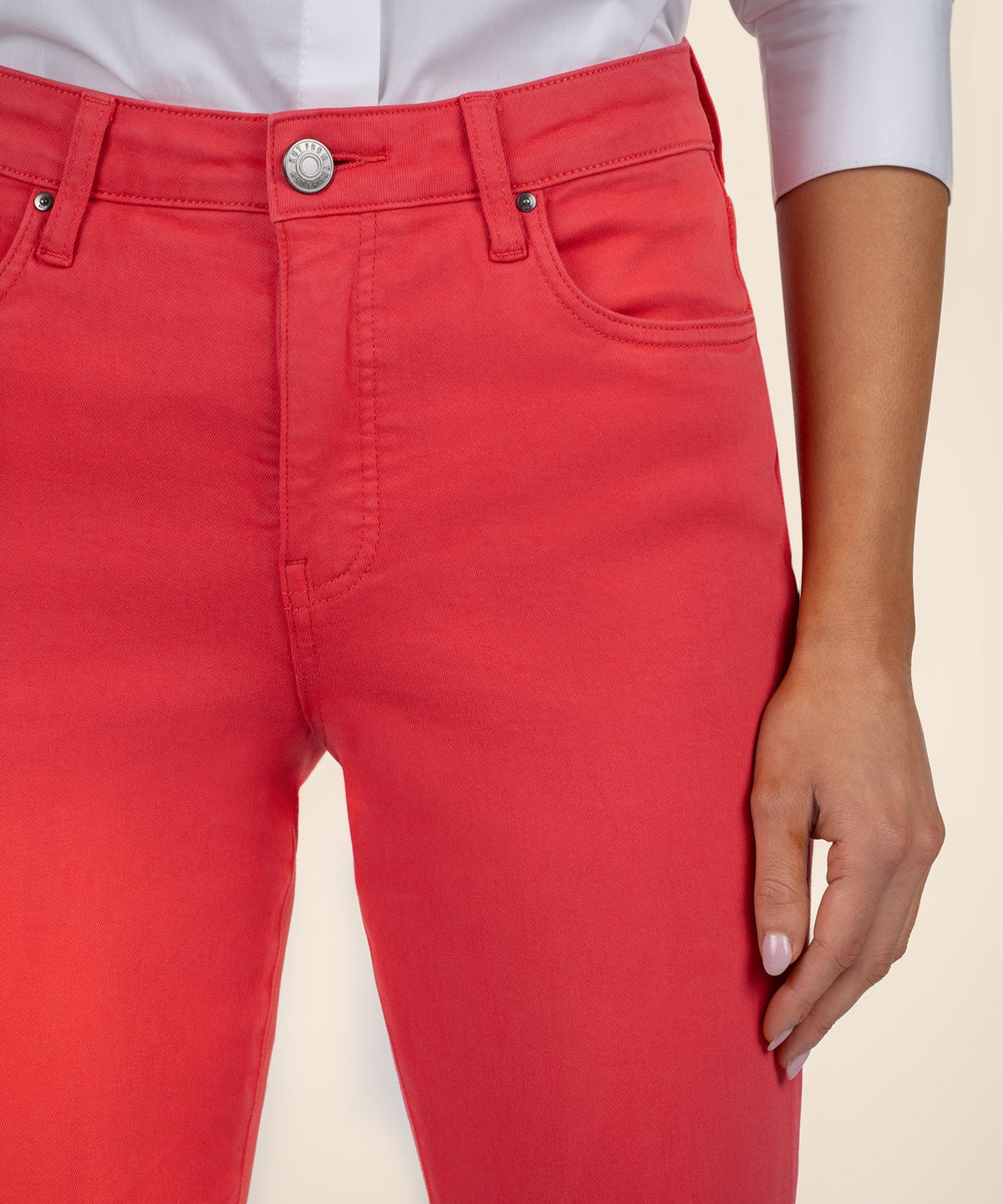 Close-up of red high-rise flare jeans with a button fly and front pockets.
