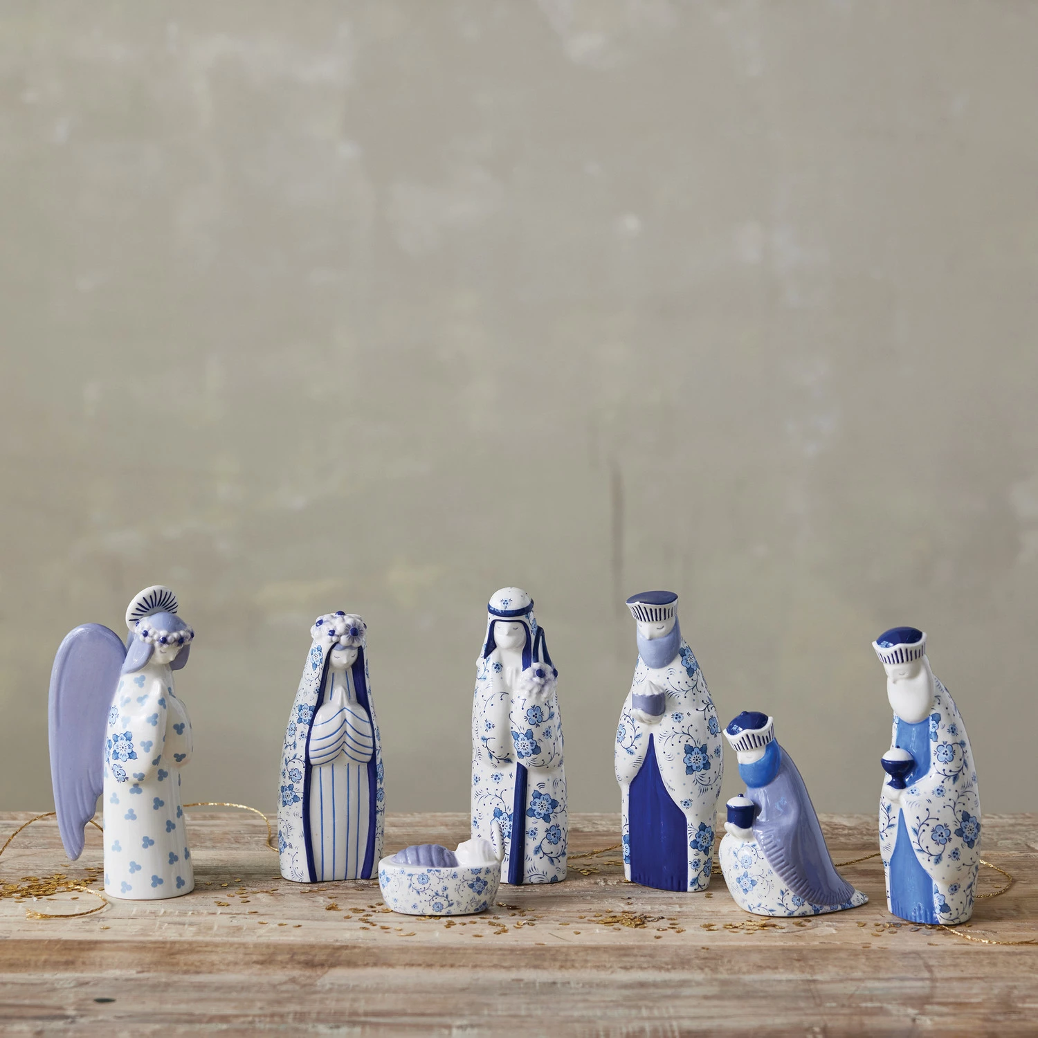 Seven-piece ceramic nativity set with blue and white floral patterns on a wooden surface.