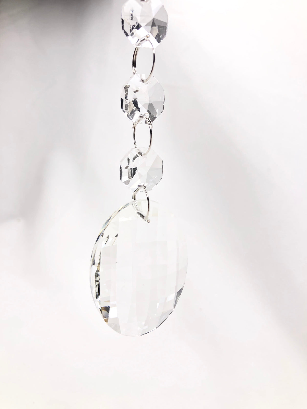 Crystal drop ornament featuring three small octagonal beads and a large faceted oval glass pendant.