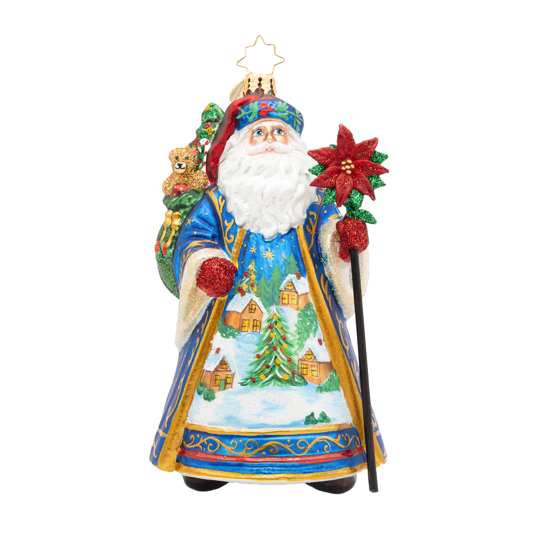 Father Christmas ornament in a blue robe with a winter village scene, holding a poinsettia staff.