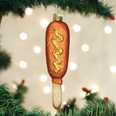 Glass corn dog Christmas ornament with a glittery mustard swirl hanging on a tree.