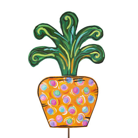 A whimsical, hand-painted wooden carrot garden stake with green leafy top and orange body decorated with colorful polka dots.