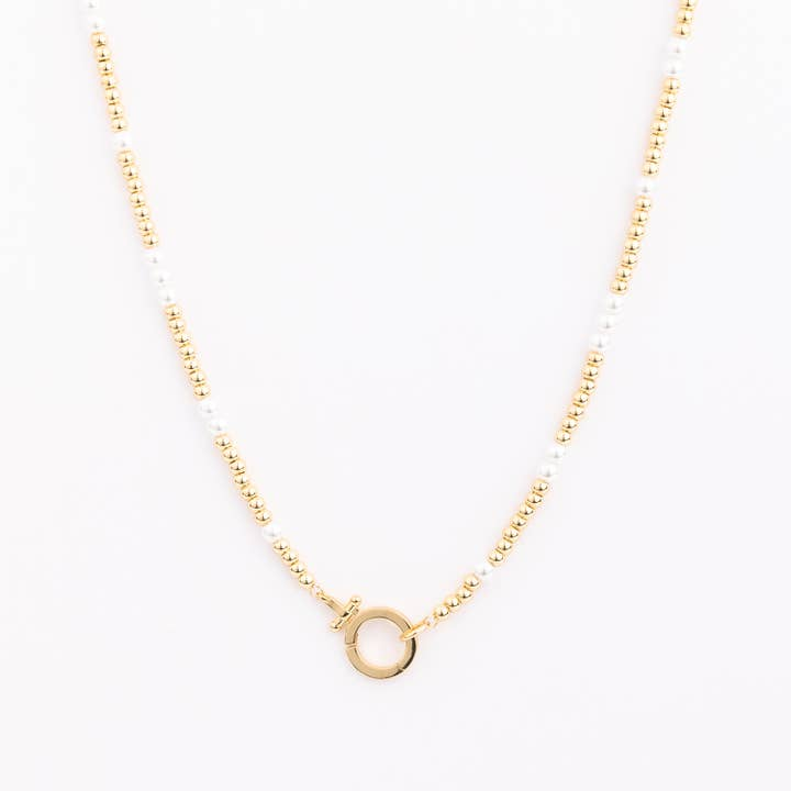 Necklace with alternating gold and white beads featuring a round gold clasp at the center.